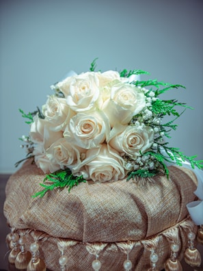 Elegant bouquet of cream-colored roses accented with silver-dusted leaves and delicate fairy lights.