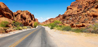 A winding highway cutting through a golden desert landscape under a bright blue sky.