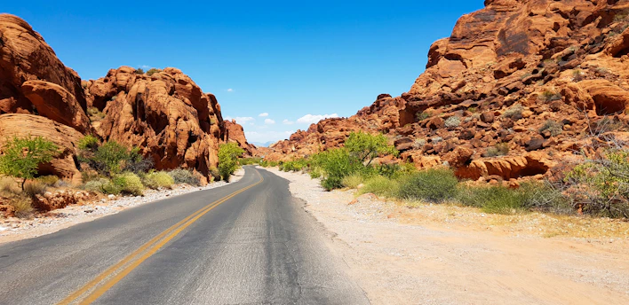A winding highway cutting through a golden desert landscape under a bright blue sky.