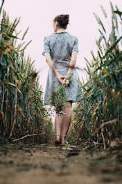 woman in gray dress standing on green grass field during daytime