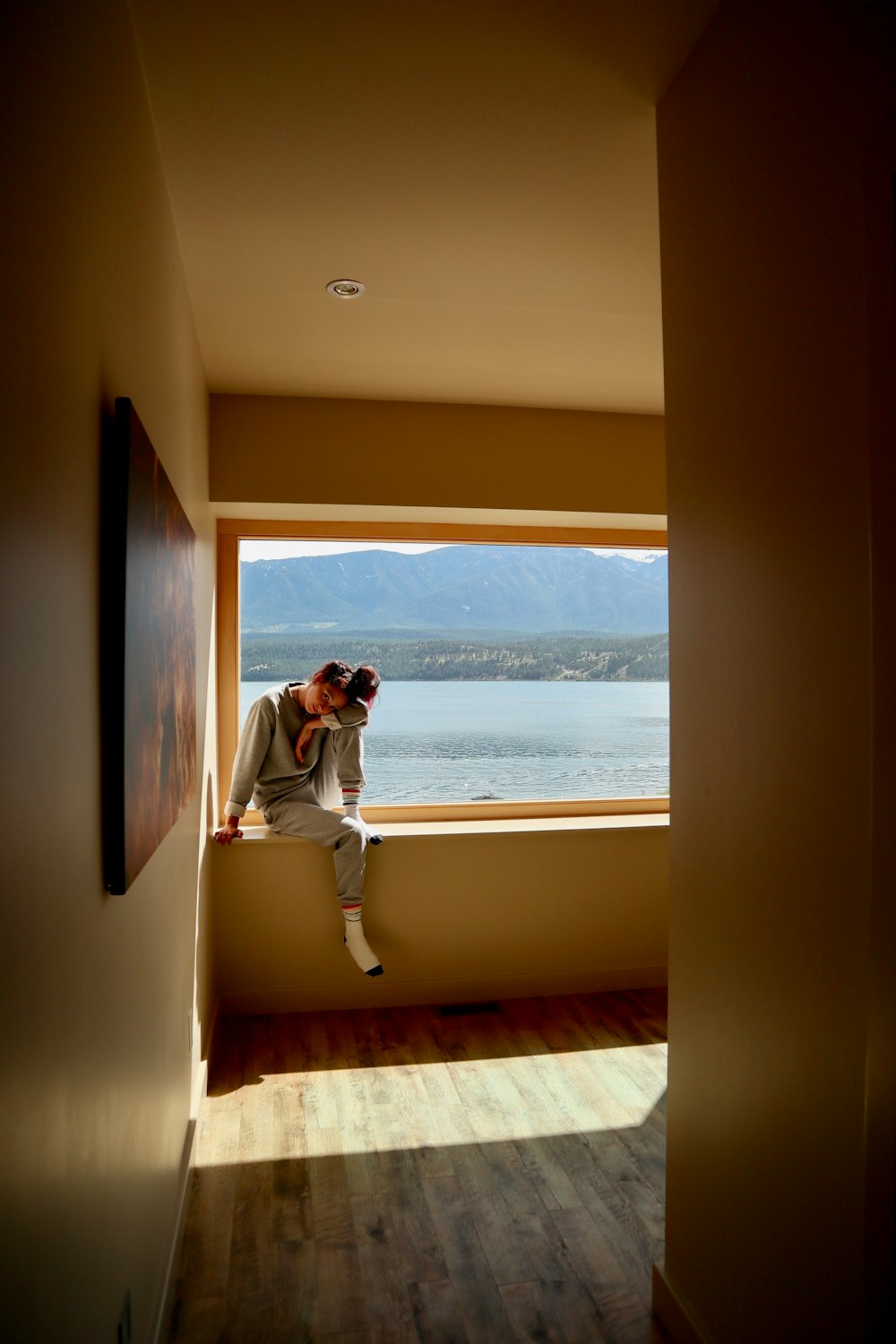 woman in white long sleeve shirt and white pants sitting on brown wooden floor during daytime