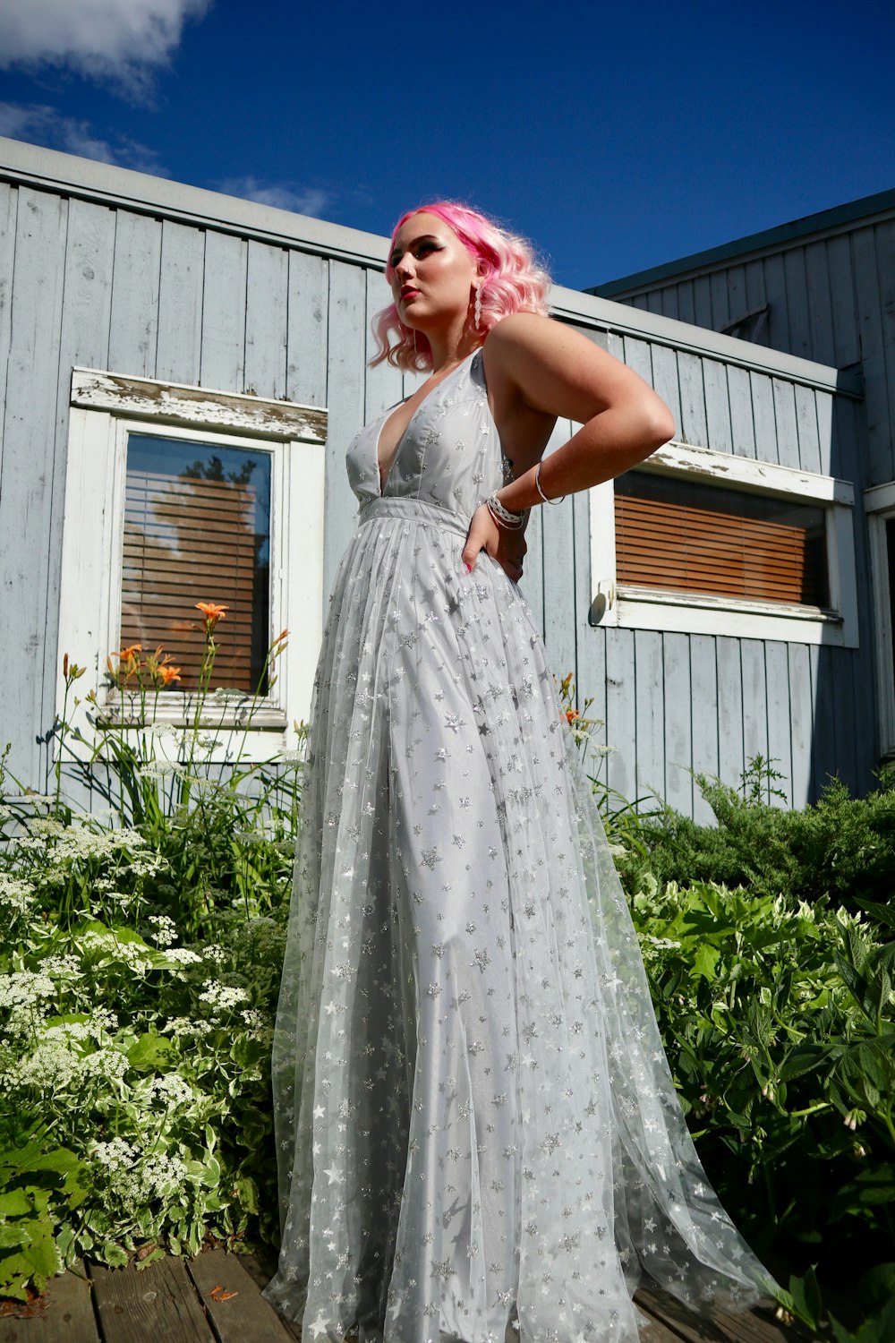 woman in white floral sleeveless dress standing near green plants during daytime