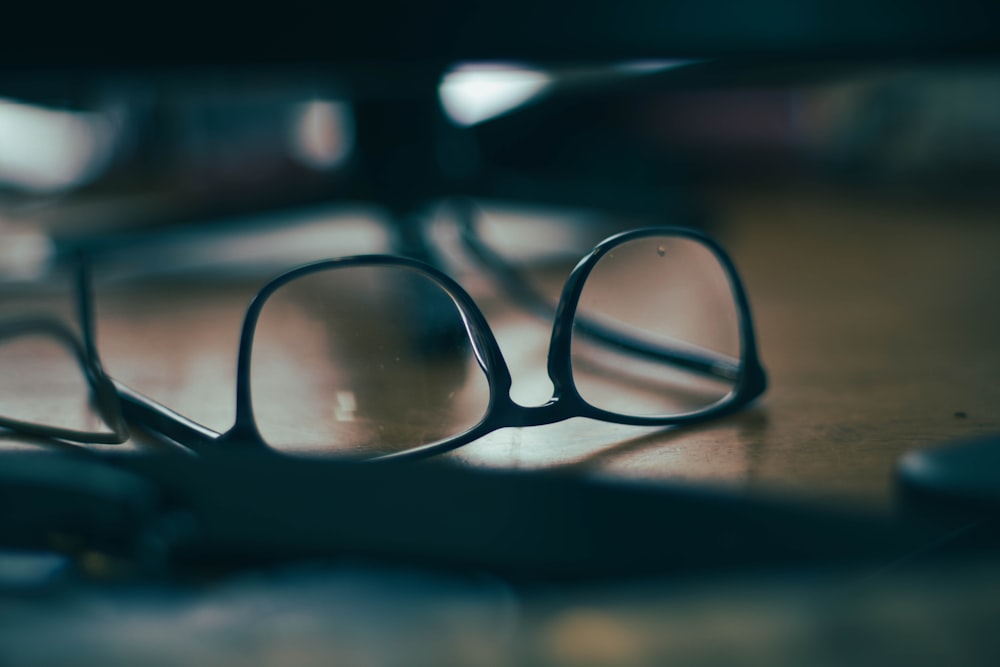 occhiali da vista con montatura nera su tavolo in legno marrone