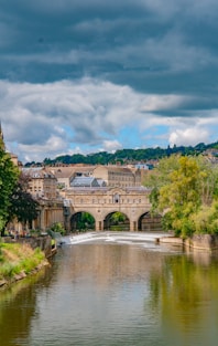 brown concrete building near river under cloudy sky during daytime