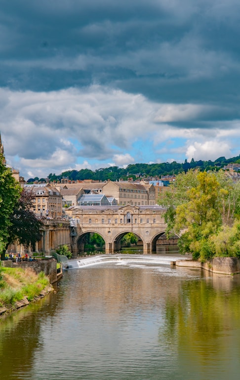 brown concrete building near river under cloudy sky during daytime