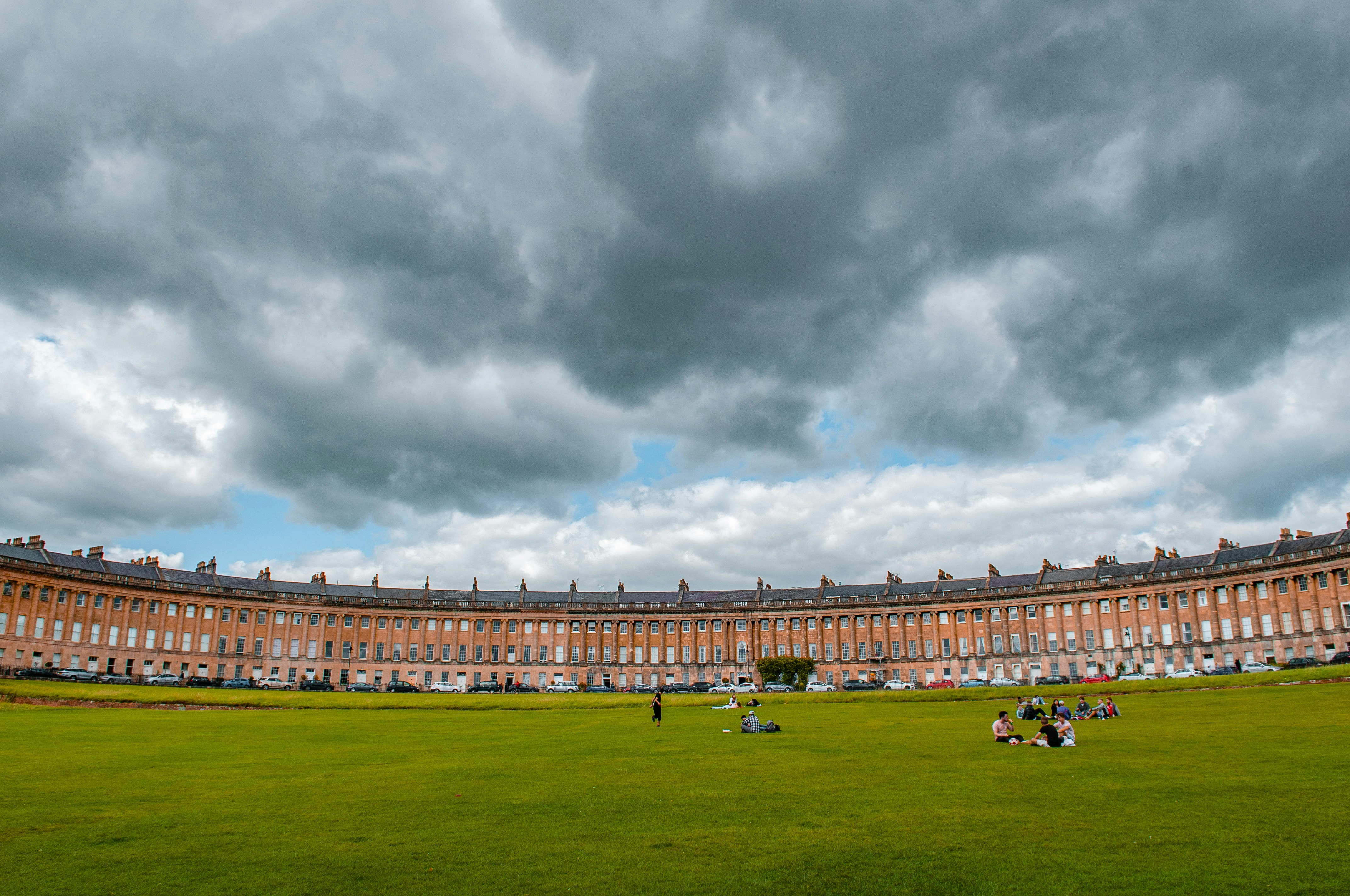 people walking on green grass field under gray clouds during daytime