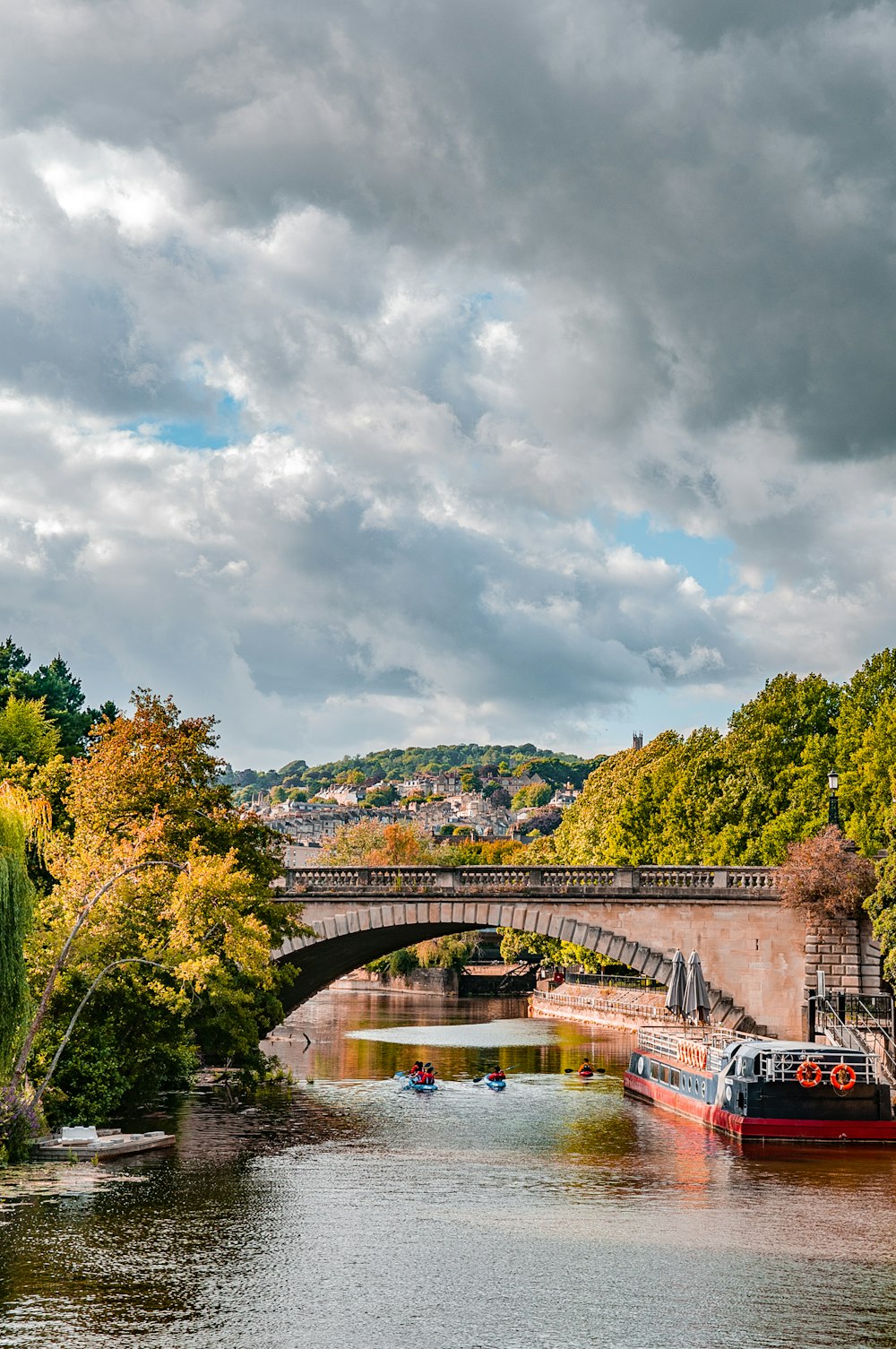 white and black boat on river near green trees under white clouds during daytime