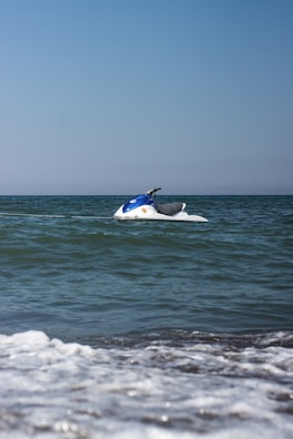A peaceful moment showing a lone jet ski floating near a small island with green trees.