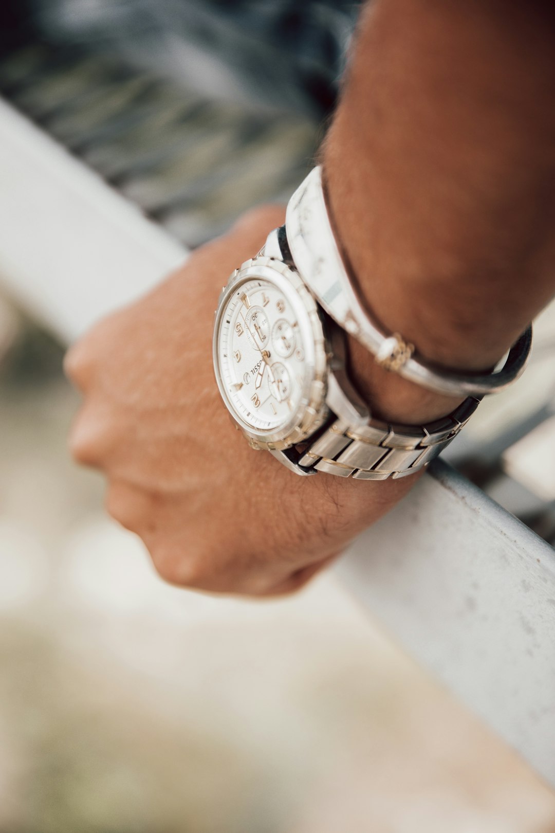 person wearing silver link bracelet round chronograph watch