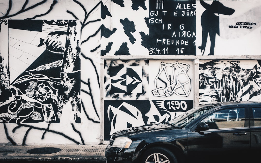 black car parked beside white wall with graffiti, Street Art in Downtown Mérida