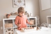 boy in orange crew neck t-shirt standing in front of white wooden table with cupcakes