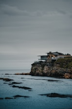 A sleek modern home overlooking the Mediterranean coastline under a clear blue sky.