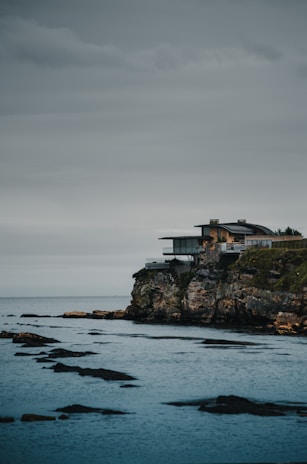 A sleek modern home overlooking the Mediterranean coastline under a clear blue sky.