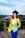 woman in yellow academic dress and black academic hat standing on top of a building during