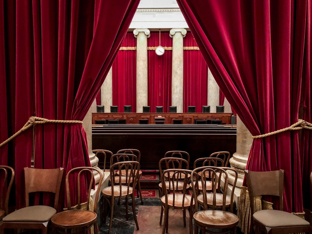 red curtain near brown wooden chairs