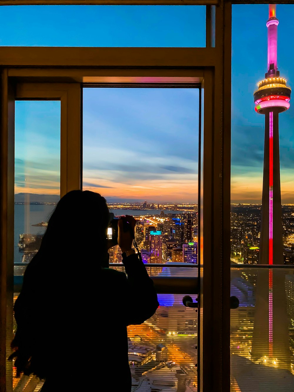 woman in black jacket taking photo of city buildings during daytime