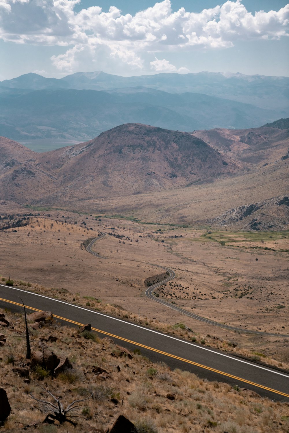 gray asphalt road near brown mountains during daytime