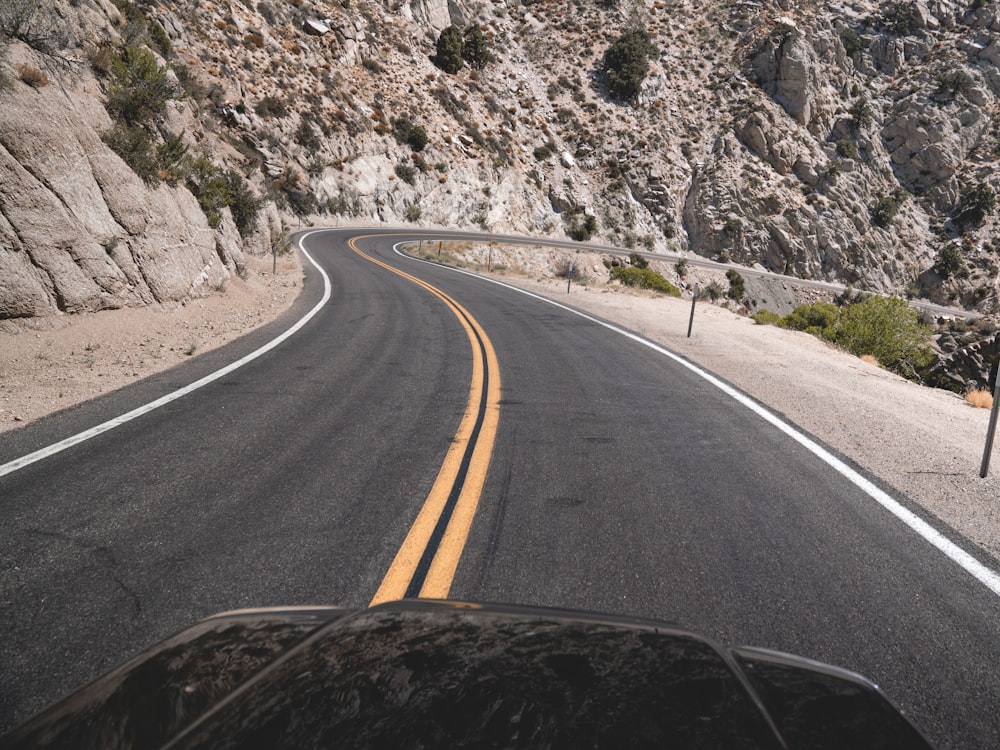 black asphalt road near gray rocky mountain during daytime