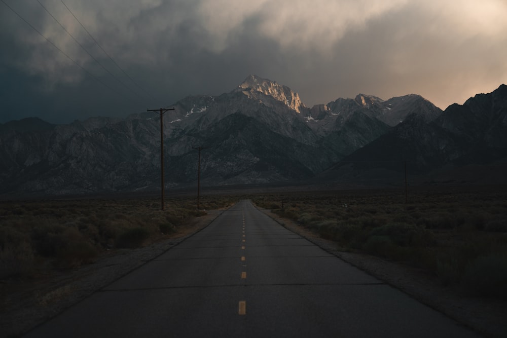 灰色の空の下の山の近くの灰色のコンクリート道路