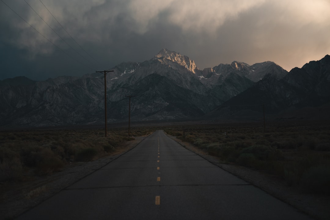 gray concrete road near mountain under gray sky,