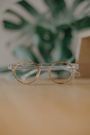 Close-up of stylish eyeglasses with twisted vine-inspired frames resting on a wooden table.
