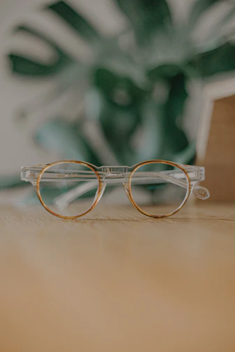 Close-up of stylish eyeglasses with twisted vine-inspired frames resting on a wooden table.