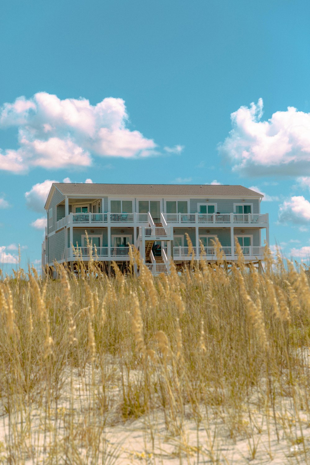 white and blue wooden house on brown grass field under blue and white cloudy sky during