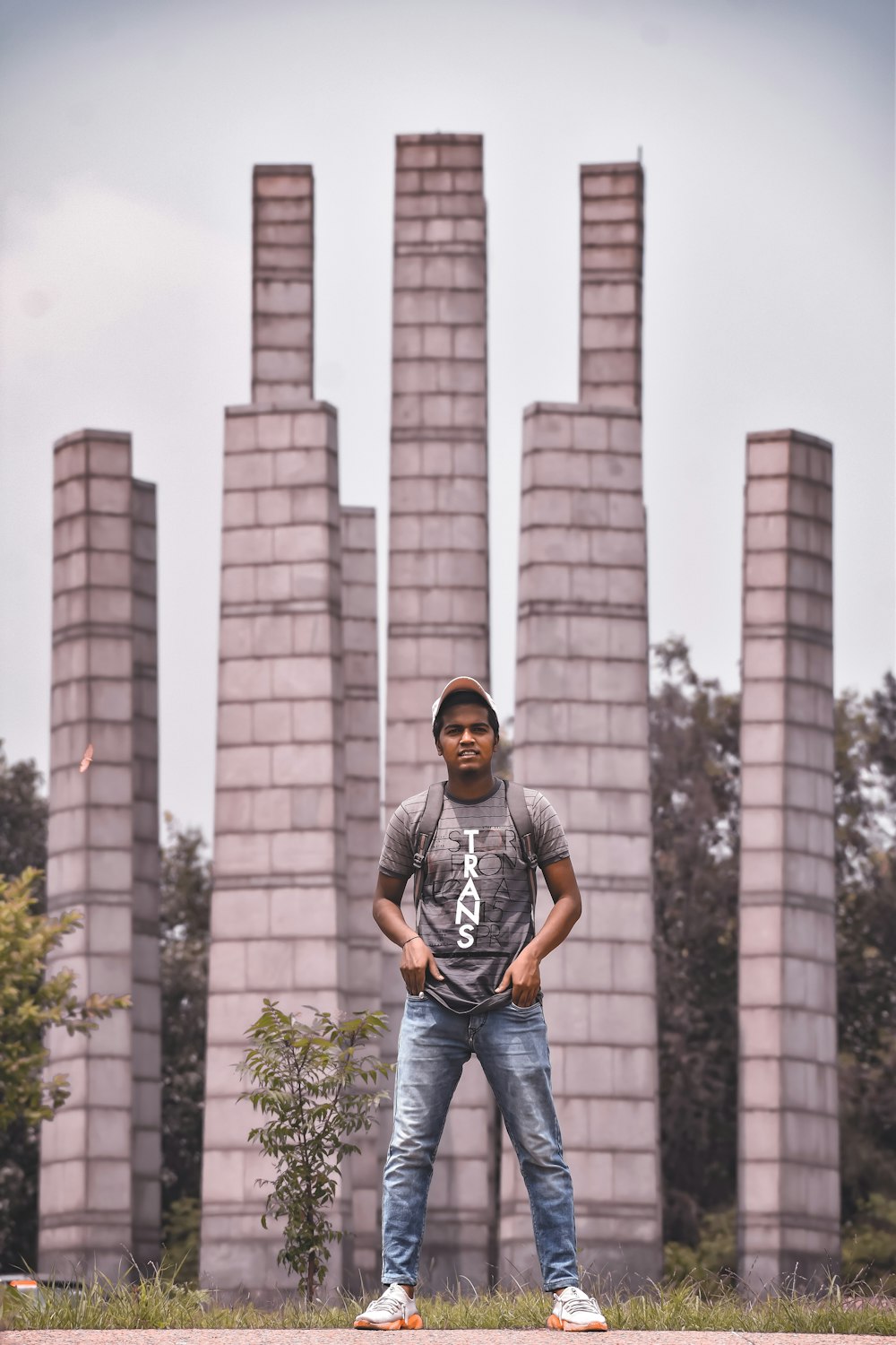 man in gray crew neck t-shirt and blue denim jeans standing near green trees during