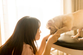 Mujer besando a un perro marrón de pelo corto.