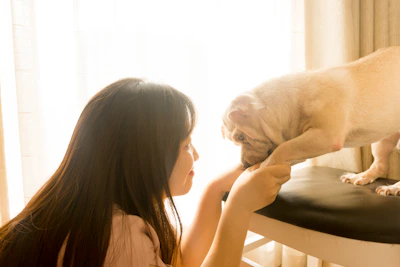 Mujer besando a un perro marrón de pelo corto.