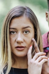 Close-up of a person gently massaging their jaw with a calm expression