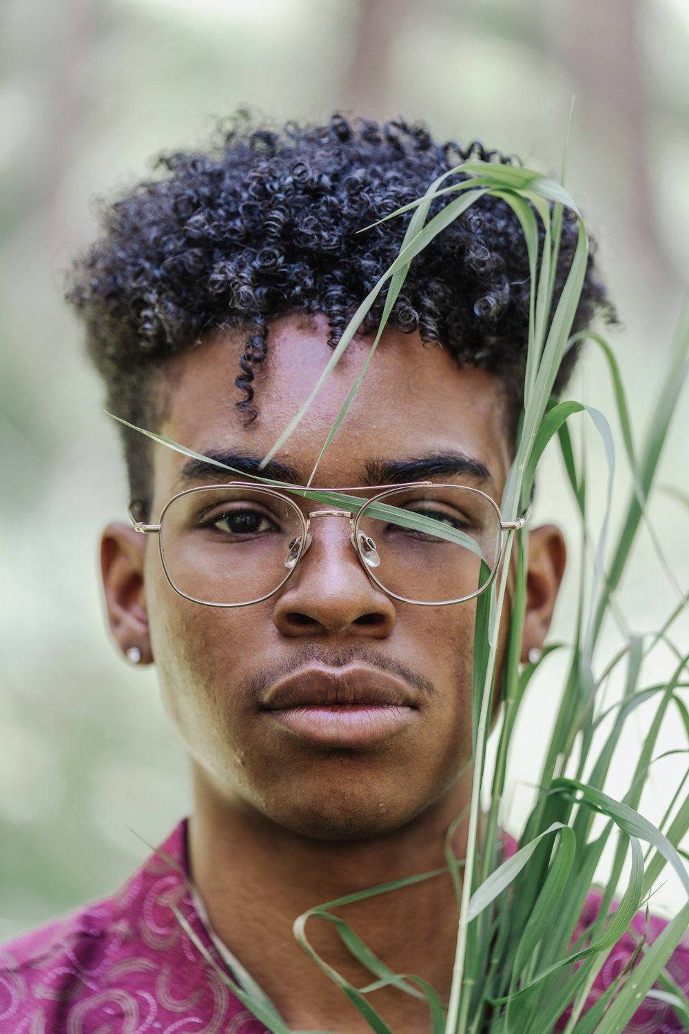 a man with glasses holding a plant in front of his face