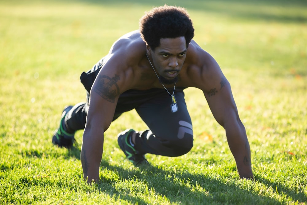 man in black shorts and black and white nike shoes lying on green grass field during