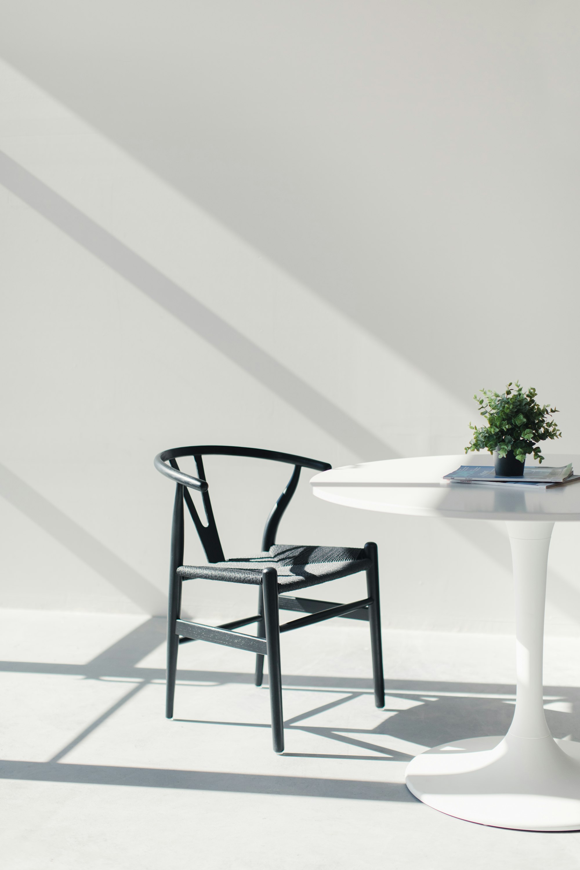 A Wishbone chair in a brightly lit with tulip table