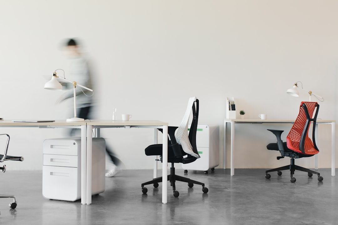 A person walking through a modern, minimalist office of chairs and desks.