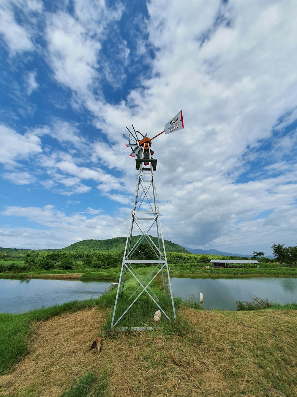 white and red windmill near lake under blue sky during daytime