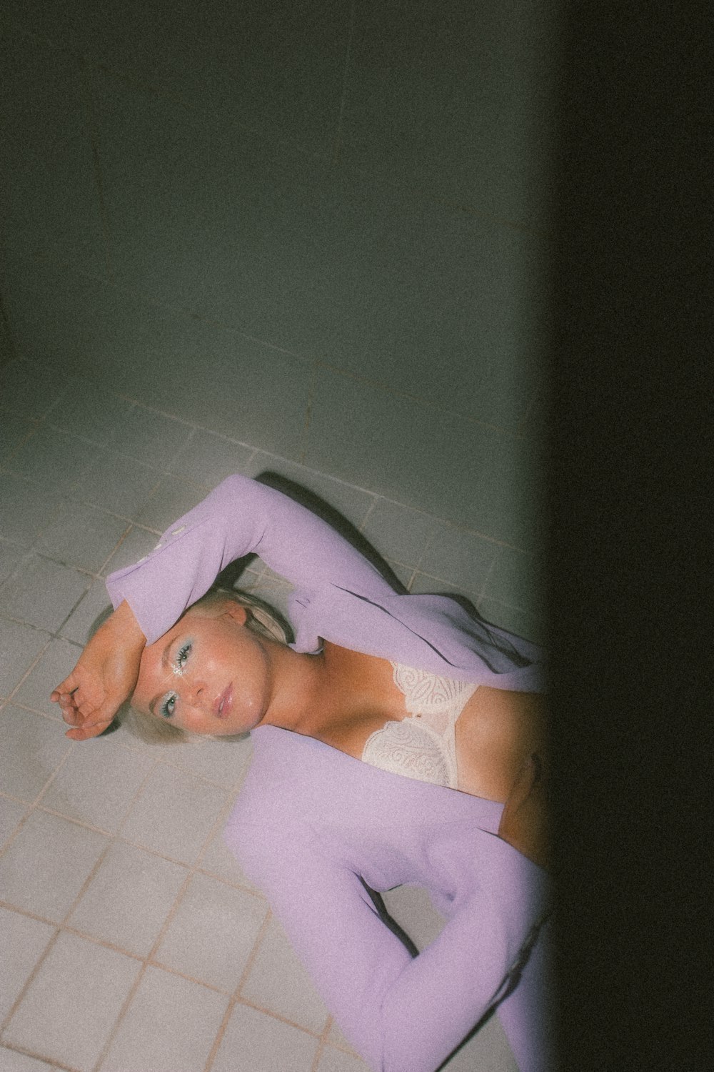 woman in white tank top lying on white ceramic floor tiles