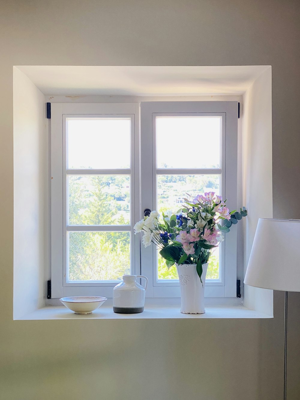 white petaled flowers in white ceramic vase on white table