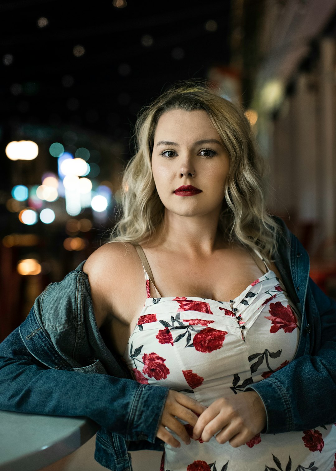 woman in red and white floral spaghetti strap top and blue denim jacket