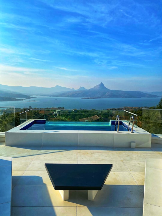 white and blue swimming pool near green mountains during daytime in Pavana India