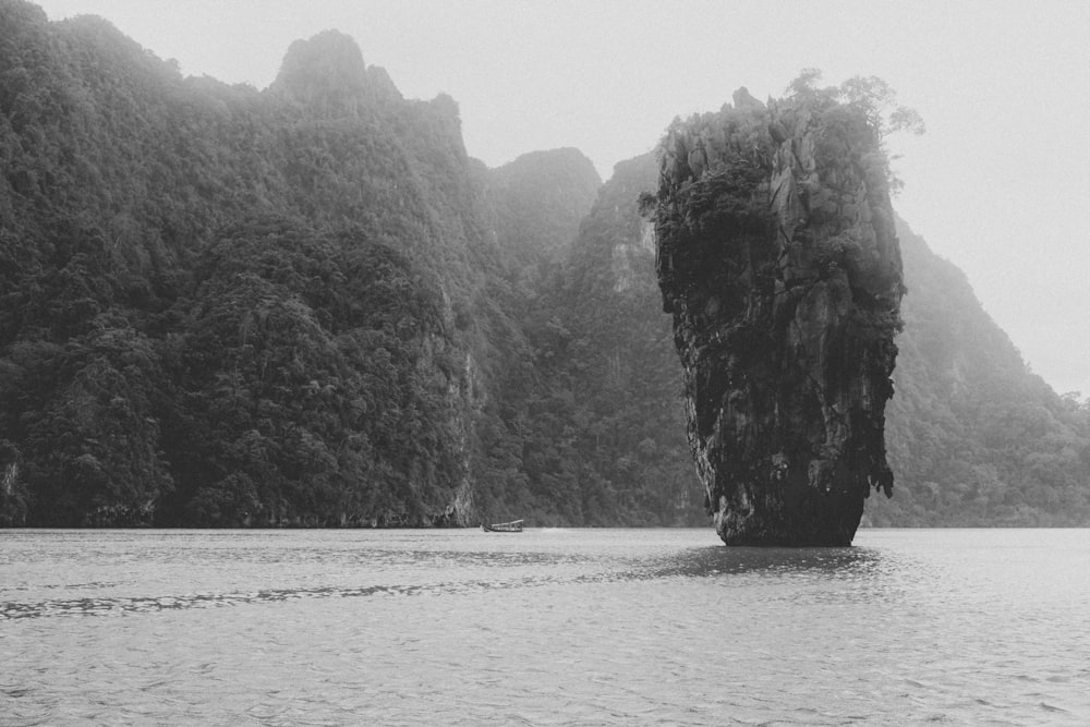 grayscale photo of rock formation on body of water