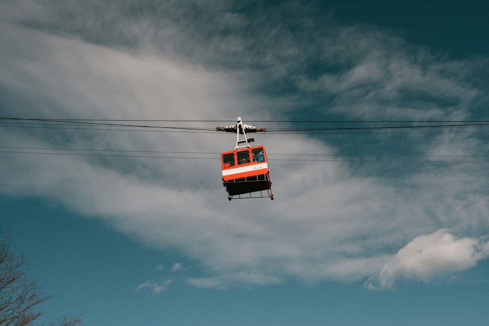 A red Hakone Ropeway cable car suspended against a bright blue sky