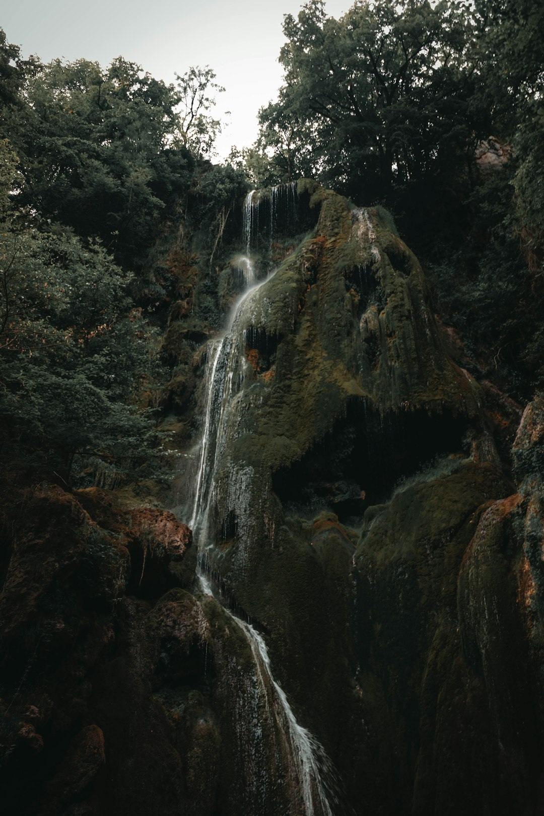 water falls on brown rocky mountain during daytime