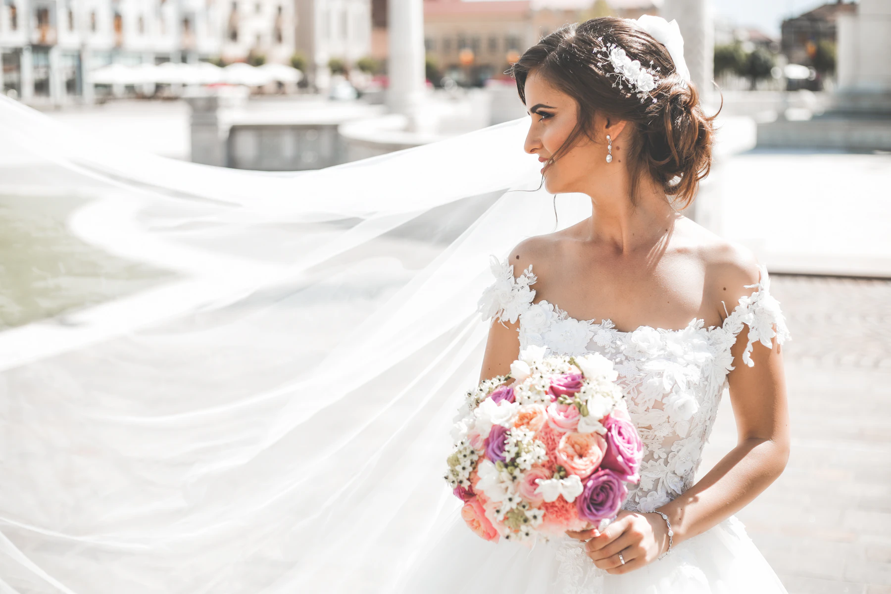 Bride in an off-shoulder lace gown with a long veil spread behind her