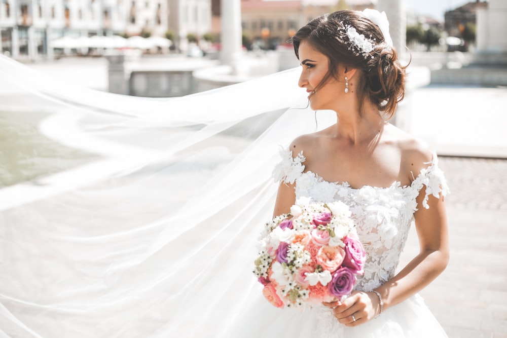 Frau im weißen Brautkleid mit Blumenstrauß