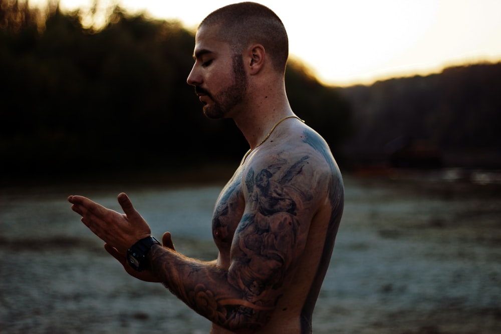 topless man with body tattoo standing on water during daytime