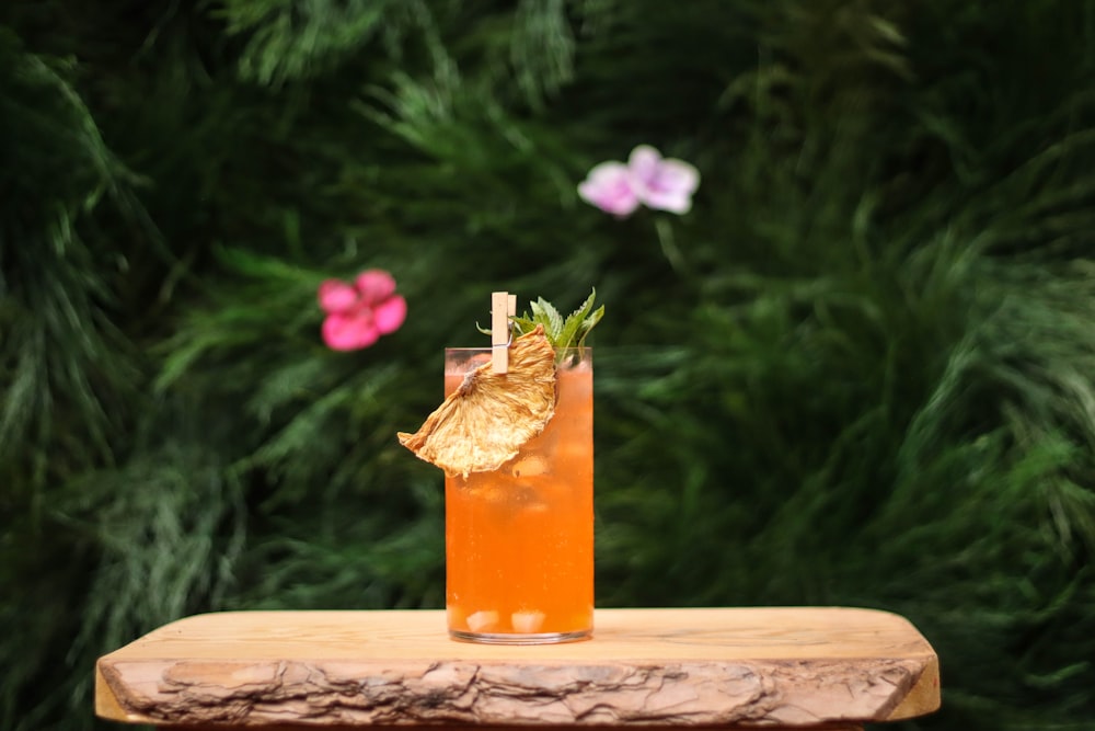 clear drinking glass with orange liquid on brown wooden table