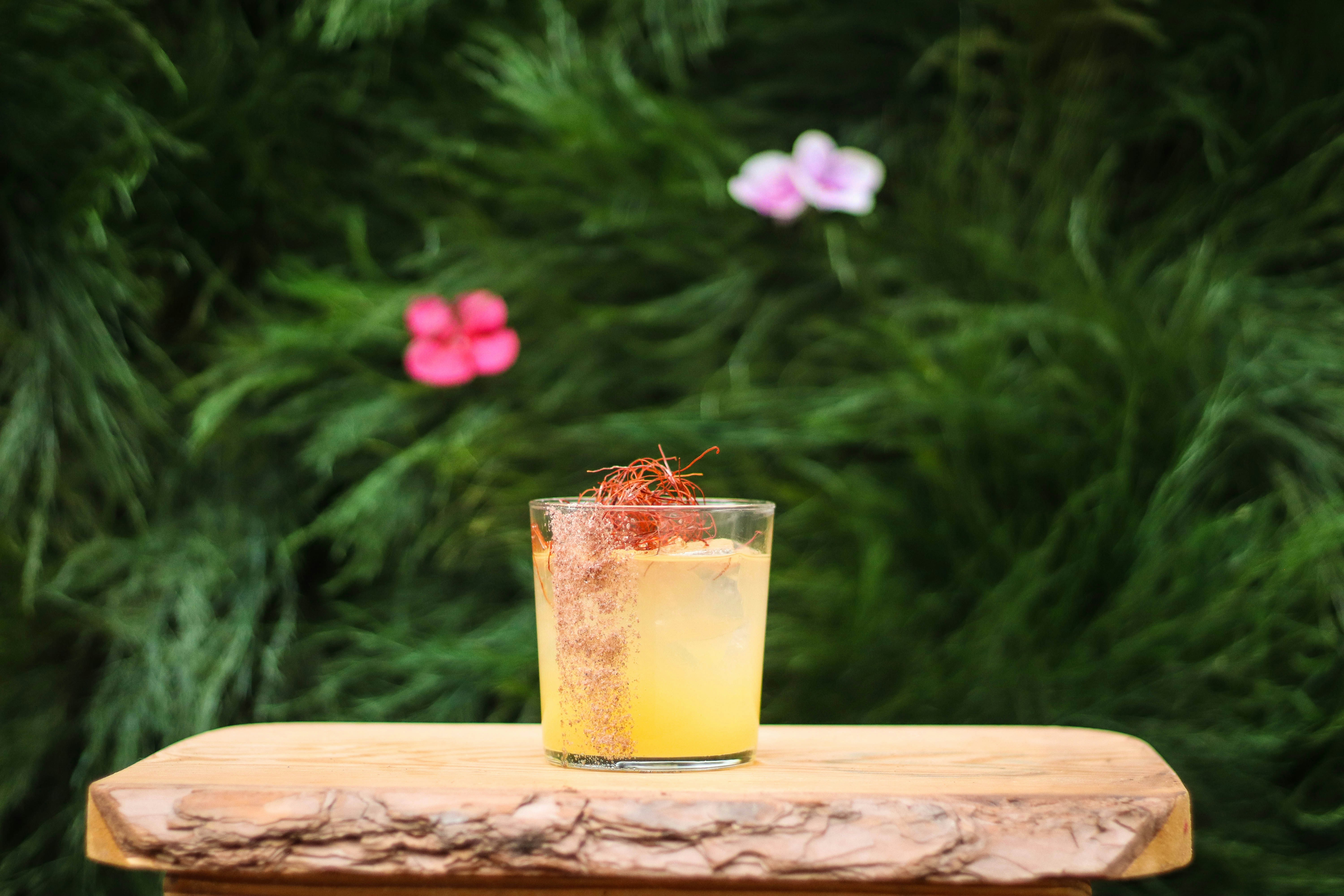 clear drinking glass with yellow liquid on brown wooden table, 