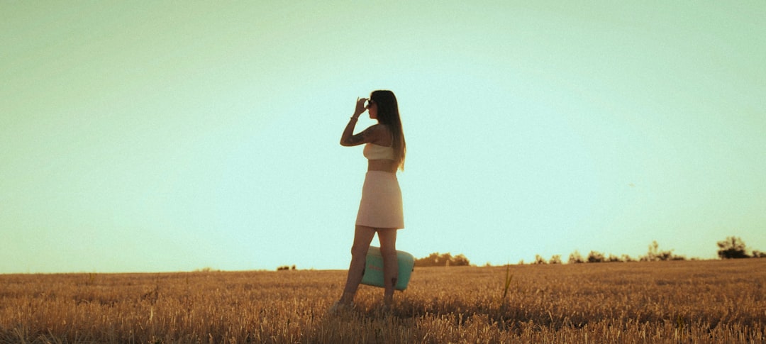 woman in white dress standing on brown grass field during daytime