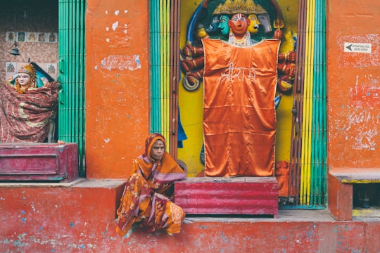 man in orange and yellow traditional dress standing beside red concrete wall in Varanasi India